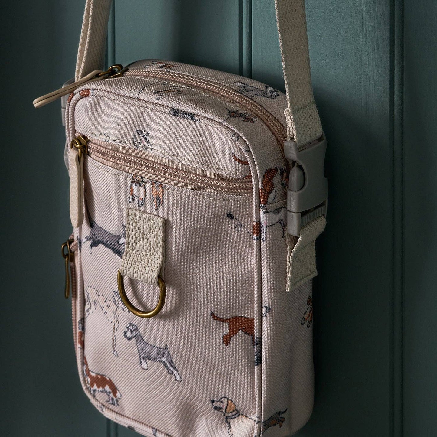 Small beige crossbody bag with dog pattern against a dark green background