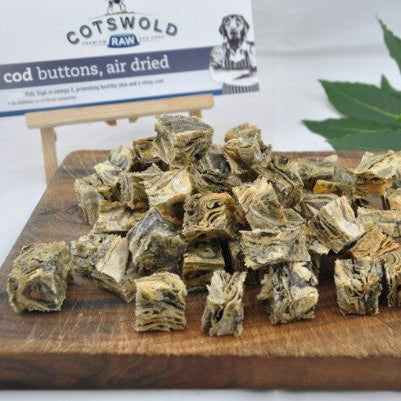 Air-dried cod buttons on a wooden board with Cotswold Raw packaging in the background.